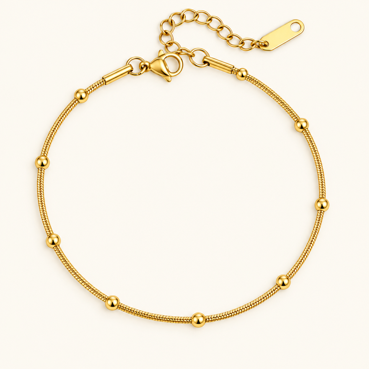 Biddy ball Bracelet with a gold-tone snake chain and polished gold balls on an ivory background