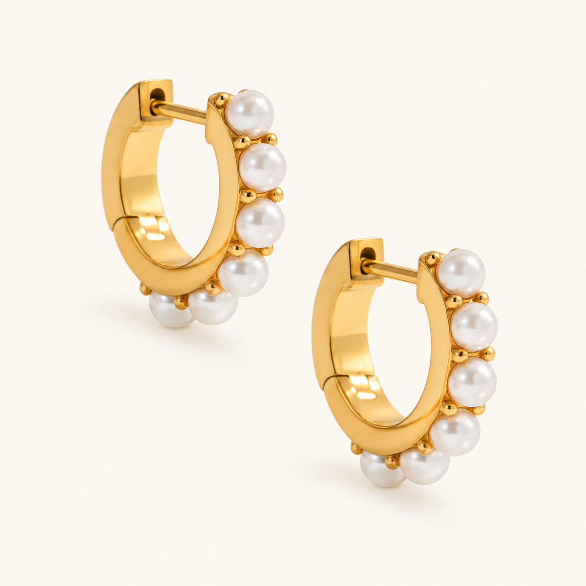 Golden Pearl Rim Hoops with white pearl details along gold-tone rims, arranged diagonally on an ivory background