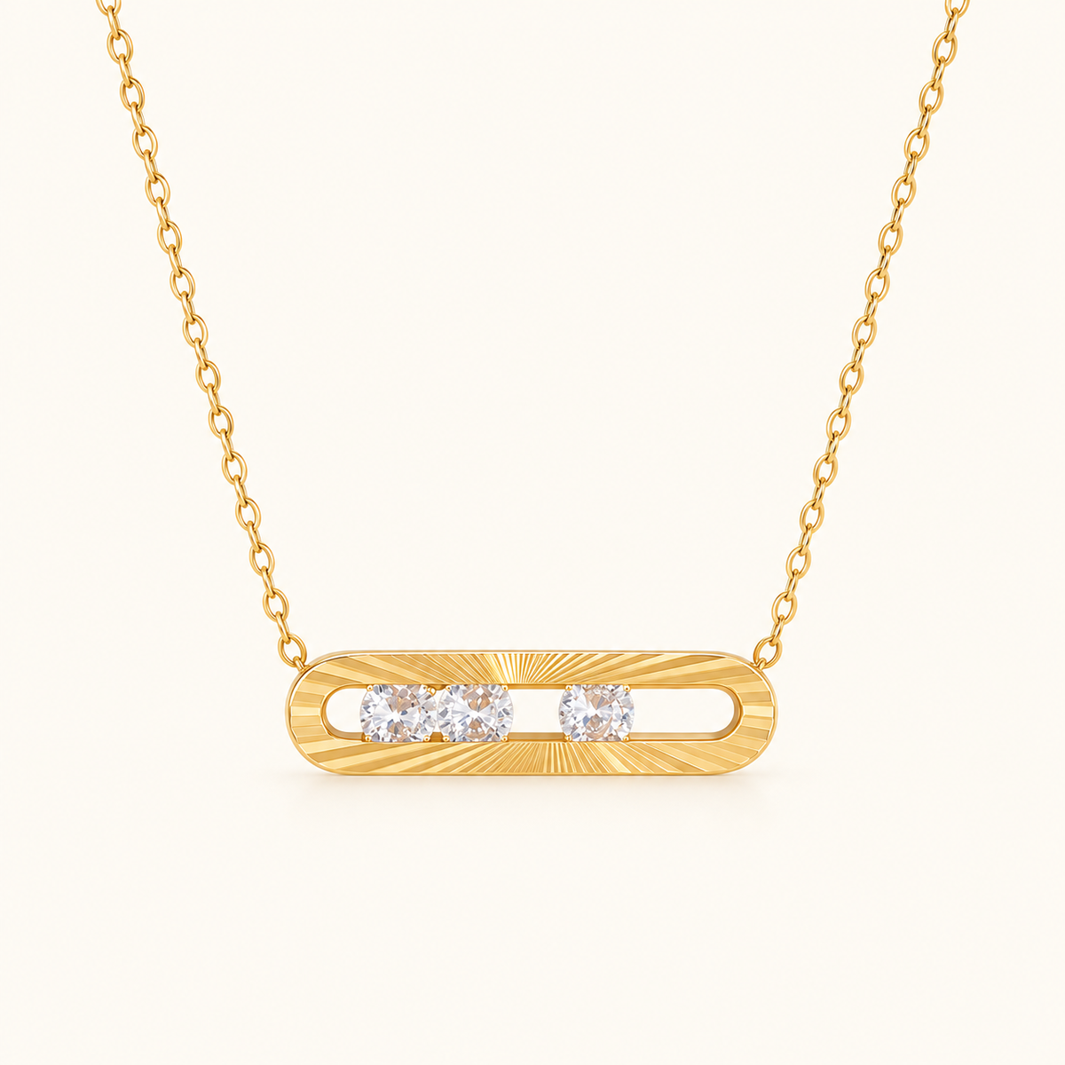 Nova Slider Necklace with a gold-tone textured bar pendant and three clear stones on an ivory background