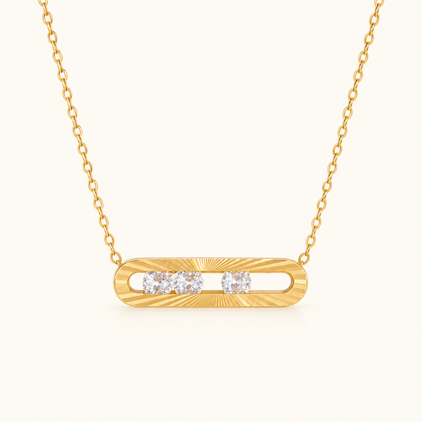 Nova Slider Necklace with a gold-tone textured bar pendant and three clear stones on an ivory background