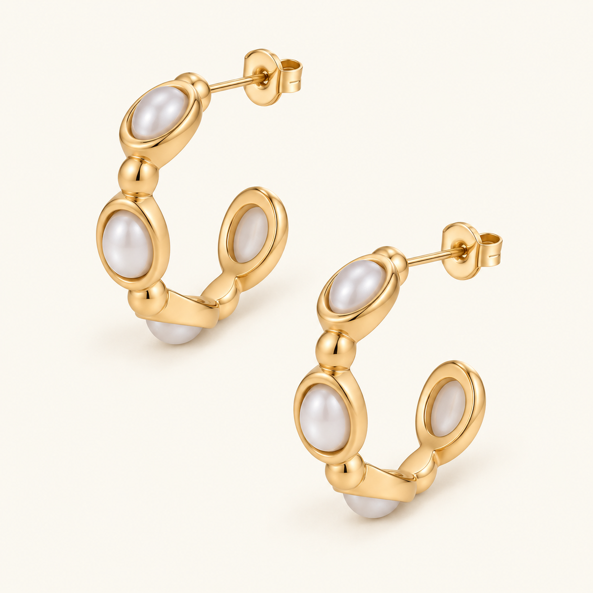 Oval Pearl Insert Hoops with white pearl details in polished gold-tone oval settings on an ivory background