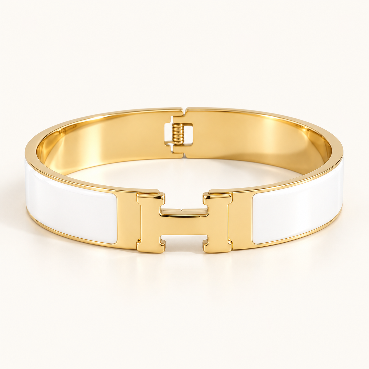 Thick gold and white H bangle on a warm ivory background